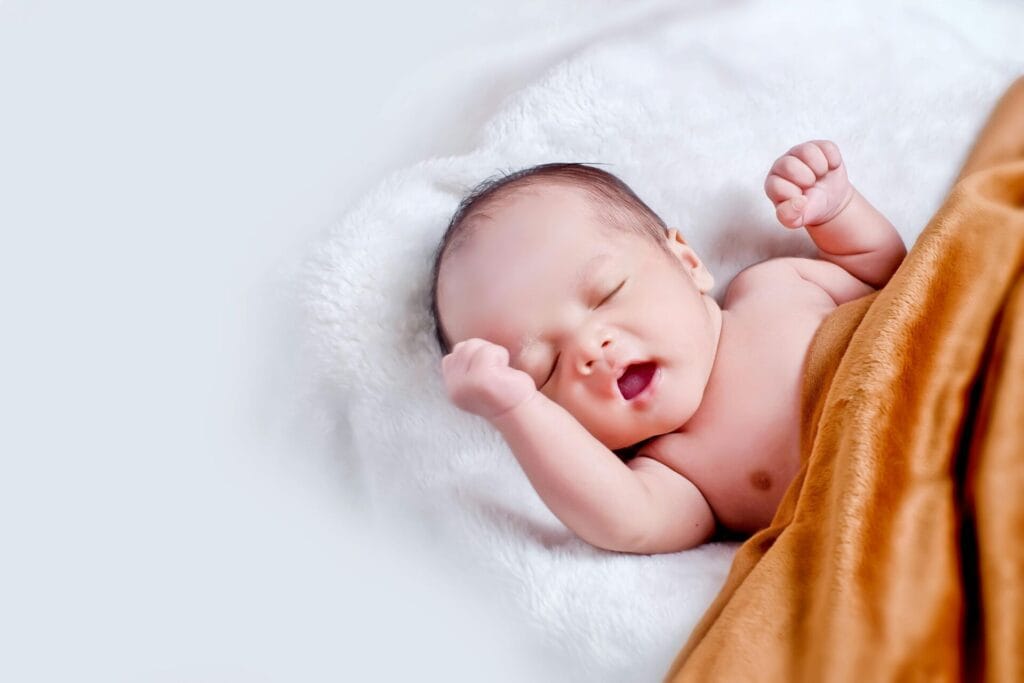 Baby lying on white fur with brown blanket